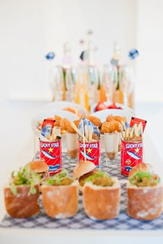 a table topped with mini sandwiches and cups filled with food