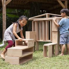 two children playing with wooden blocks in the grass