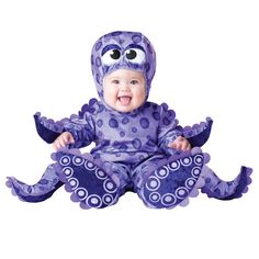 a baby in a blue octopus costume sitting on the ground with its mouth open and eyes wide open