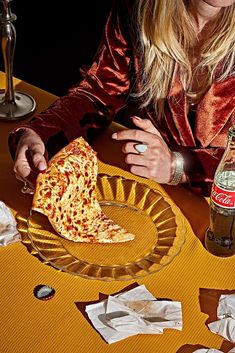 a woman sitting at a table with a slice of pizza in front of her