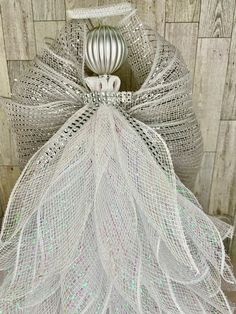 a white mesh angel ornament hanging on a wooden wall