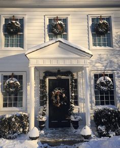 a white house with wreaths on the front door