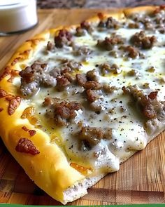 a pizza sitting on top of a wooden cutting board next to a glass of milk