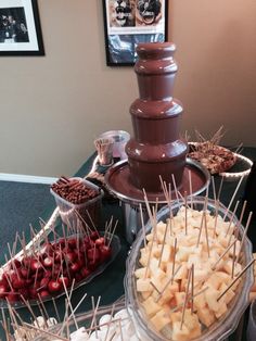 a chocolate fountain is surrounded by desserts and candies