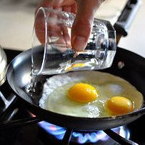 two eggs being fried in a frying pan on top of a gas burner