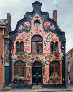 an old building with flowers painted on it's side and windows in the front