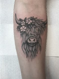 a black and white photo of a cow with flowers on it's head tattoo