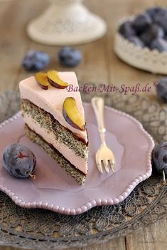 a piece of cake on a plate with blueberries and plums next to it