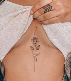 a woman's stomach with a rose tattoo on her left side ribcage