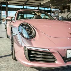 a pink porsche parked in front of a building