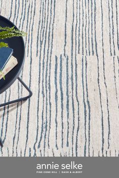 an area rug with blue and white stripes on the floor, next to a plant