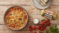 a pizza sitting on top of a wooden table next to tomatoes and other food items