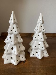 two ceramic christmas trees sitting on top of a wooden table