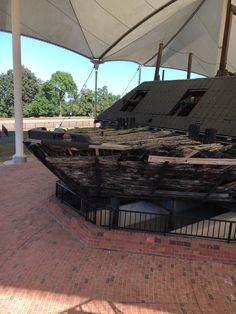 an old boat sitting on top of a brick floor next to a white awning