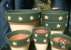 four pots with flowers painted on them are sitting next to a cactus plant in a pot