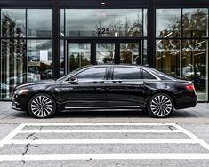 a black car is parked in front of a large building with glass doors and windows