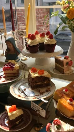 a table topped with lots of different types of cakes and cupcakes on top of plates