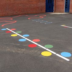 an empty parking lot with colorful circles painted on the pavement and in front of a brick building