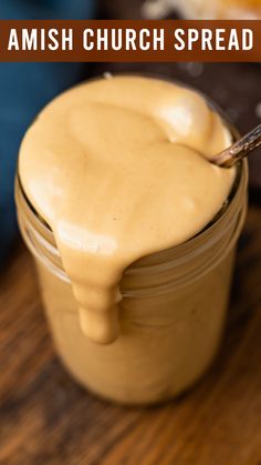 a spoon in a jar filled with some kind of mustard spread on top of a wooden table