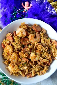 a white bowl filled with rice and shrimp on top of mardi gras decorations