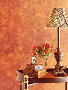 a leopard print lamp on a table next to a vase with red flowers and books