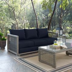 an outdoor living room with blue couches and coffee table in the foreground, surrounded by trees