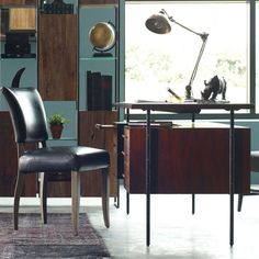 a chair and desk in front of a large window with lots of bookshelves