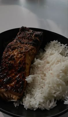 a black plate topped with rice and meat