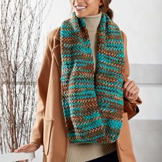 a woman wearing a knitted scarf and jacket in brown, blue and green colors