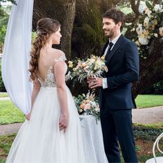 a man in a suit and tie standing next to a woman in a wedding dress