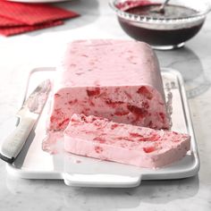 two pieces of ice cream sitting on top of a white plate next to a knife