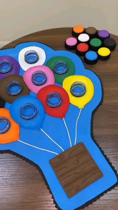 a table topped with lots of different colored items on top of a wooden table covered in paper