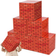 a person holding a large red brick in front of a stack of bricks on top of each other