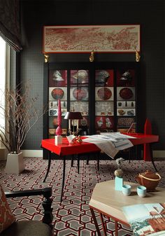 a living room filled with furniture and pictures on the wall above red table cloths