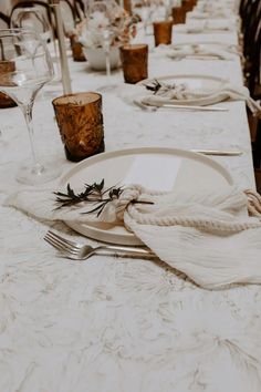 the table is set with white linens, silverware and place settings for dinner