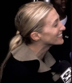 a woman with blonde hair is smiling and talking to someone on the red carpet at an event