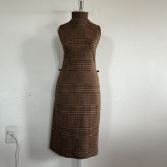 "Introducing a true vintage gem from the 1970s - the brown and gold glittery houndstooth pattern sleeveless dress by Sharagano Paris. This stunning dress is a rare find that will add a touch of retro glamor to your wardrobe. This dress features a unique houndstooth pattern in a warm brown and gold glittery hue that shimmers in the light. The sleeveless design allows for easy movement, while the fitted silhouette accentuates your curves for a flattering fit. The dress also features a high necklin Retro Sleeveless Winter Dresses, Retro Brown Dress For Fall, Fitted Brown Sleeveless Dress For Fall, Vintage Plaid Sleeveless Dress, Retro Brown Midi Dress, 1970s Fitted Brown Dress, Fitted Brown 1970s Dress, Retro Sleeveless Brown Dress, Fitted Brown 1970s Style Dresses