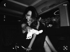 a black and white photo of a woman sitting in a car with her hand on the steering wheel