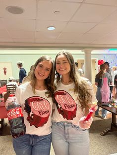 two girls standing next to each other with coca - cola on their shirts