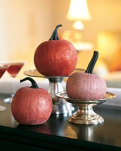 three red pumpkins sitting on top of a metal stand next to glasses and a bowl