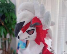 a close up of a stuffed animal with red and white feathers on it's head