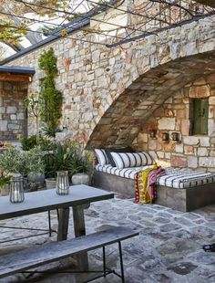 an outdoor seating area with stone walls and plants on the table next to it,