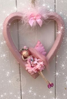 a pink heart hanging on the side of a door with a small doll in it