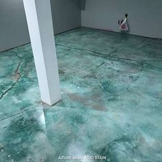 an empty room with green paint on the floor and white columns in the corner,