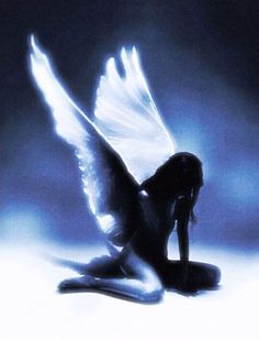 a woman sitting on the ground with her wings spread out and she is looking down