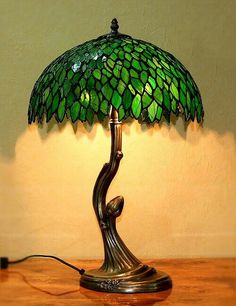 a lamp that is sitting on top of a wooden table with a green glass shade