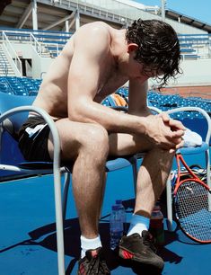 a shirtless tennis player sitting on a chair