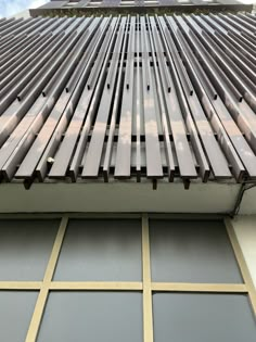 the side of a building with metal slats on it's roof and sky in the background