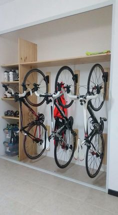 there are two bikes hanging on the wall in this bike storage area, and one is upside down