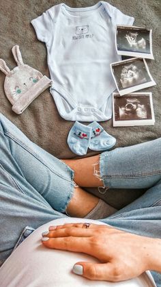 a person laying on top of a bed next to baby clothes and pictures with babies in them